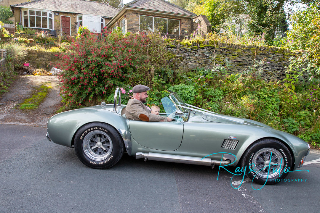 Groom and son arrive in a AC Cobra RAM 5.7 V8 1973 classic car at Holy Trinity church Hepworth