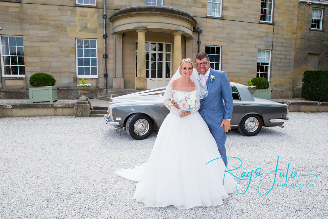 Bride with wedding flowers and dad standing outside Saltmarshe Hall. Rolls Royce bridal car in background.