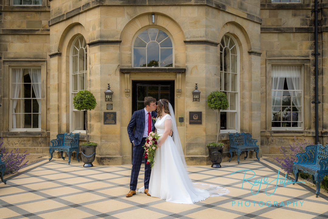 Bride and Groom kissing outside Grantley Hall main entrance