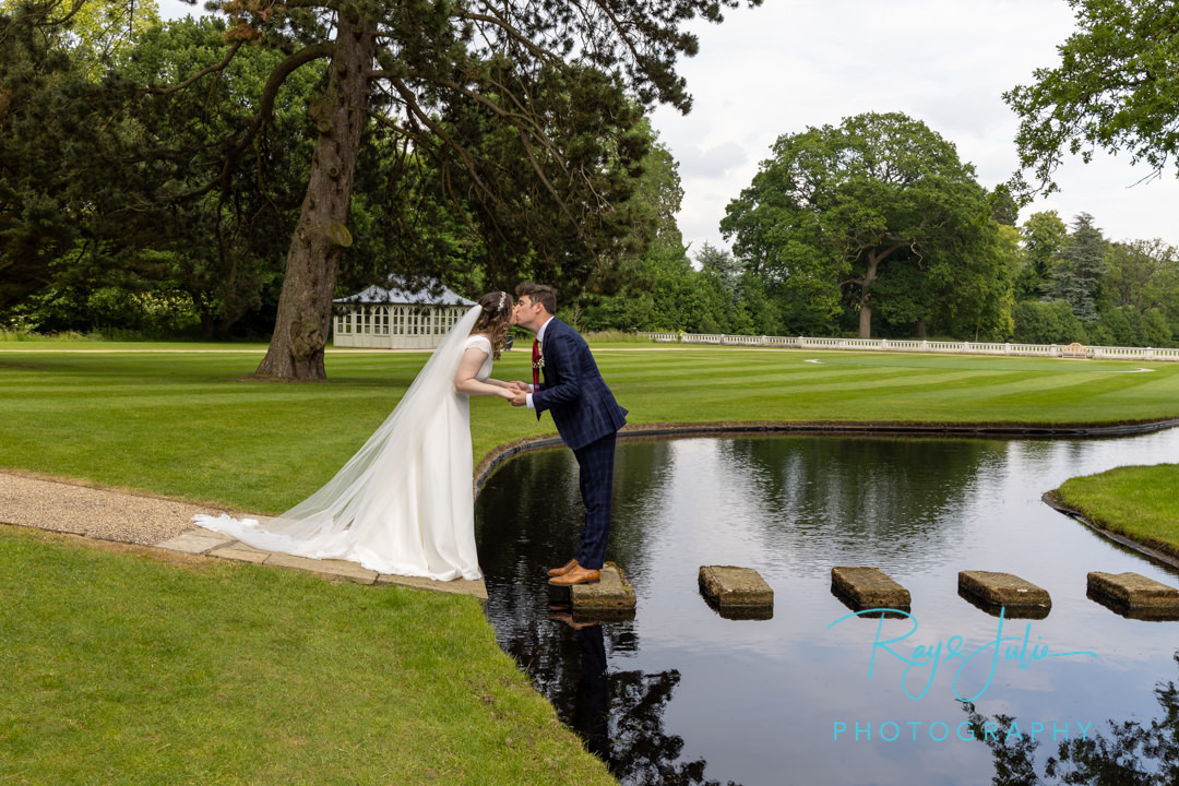 Wedding couple kissing on stepping stones at Grantley Hall