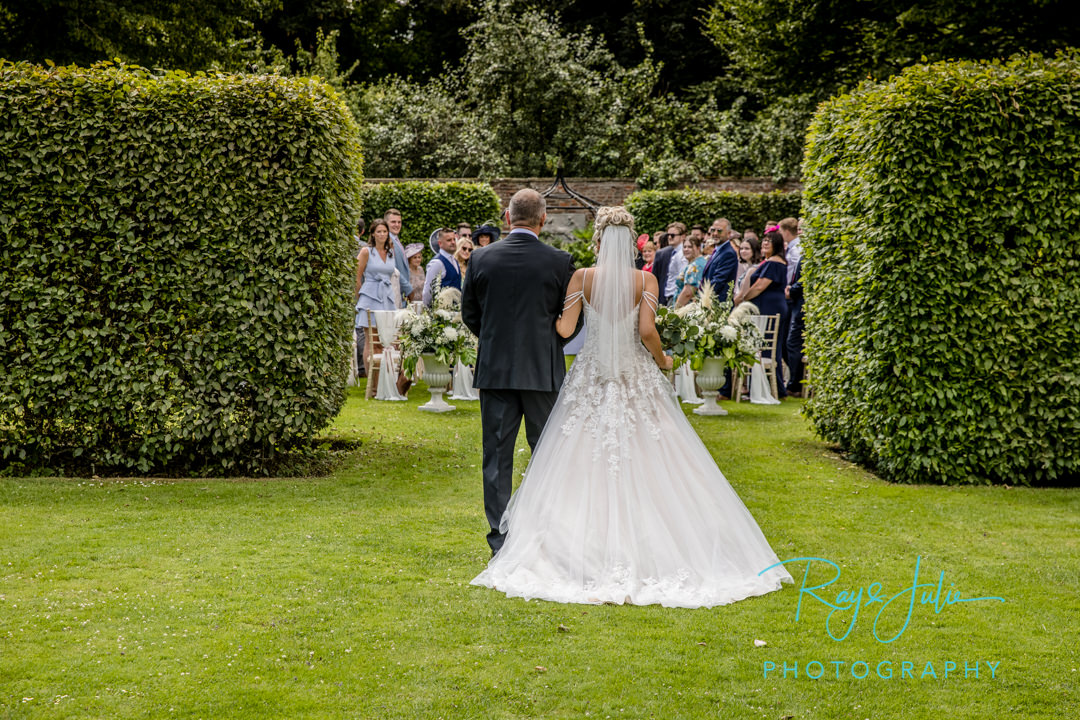 Bride and Father walking to groom at an outdoor wedding ceremony in Saltmarshe Hall's Walled Garden