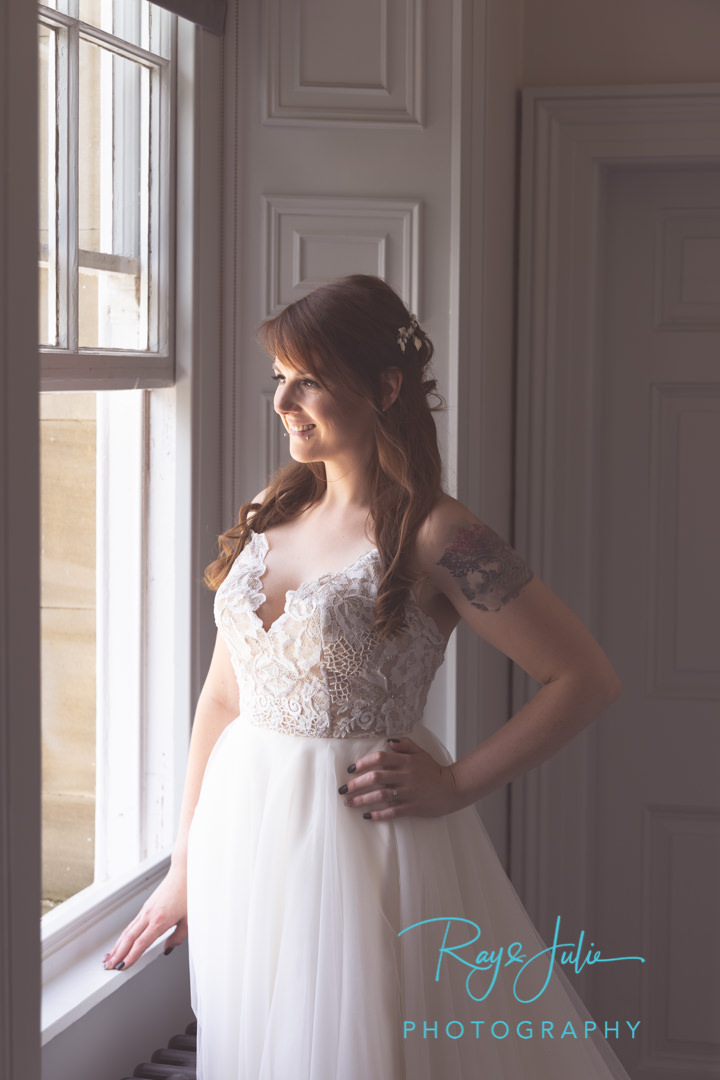 Stunning bride in wedding dress smiling looking out a window