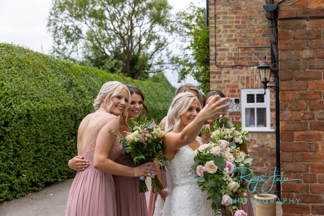 Bride and bridesmaids selfie time before wedding ceremony.