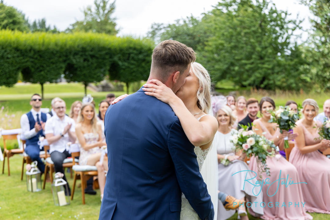 The first kiss. Guests in background clapping and smiling.