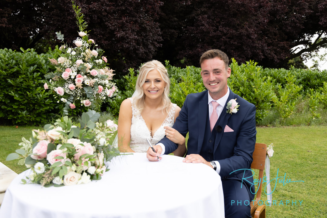 Bride and Groom signing the wedding register outdoors