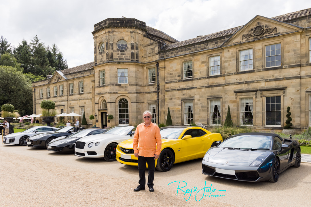 Groom stood outside front of Grantley Hall with super cars behind