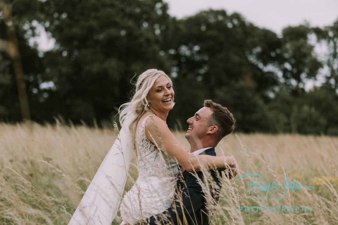 Groom picking up his happy bride in long grass