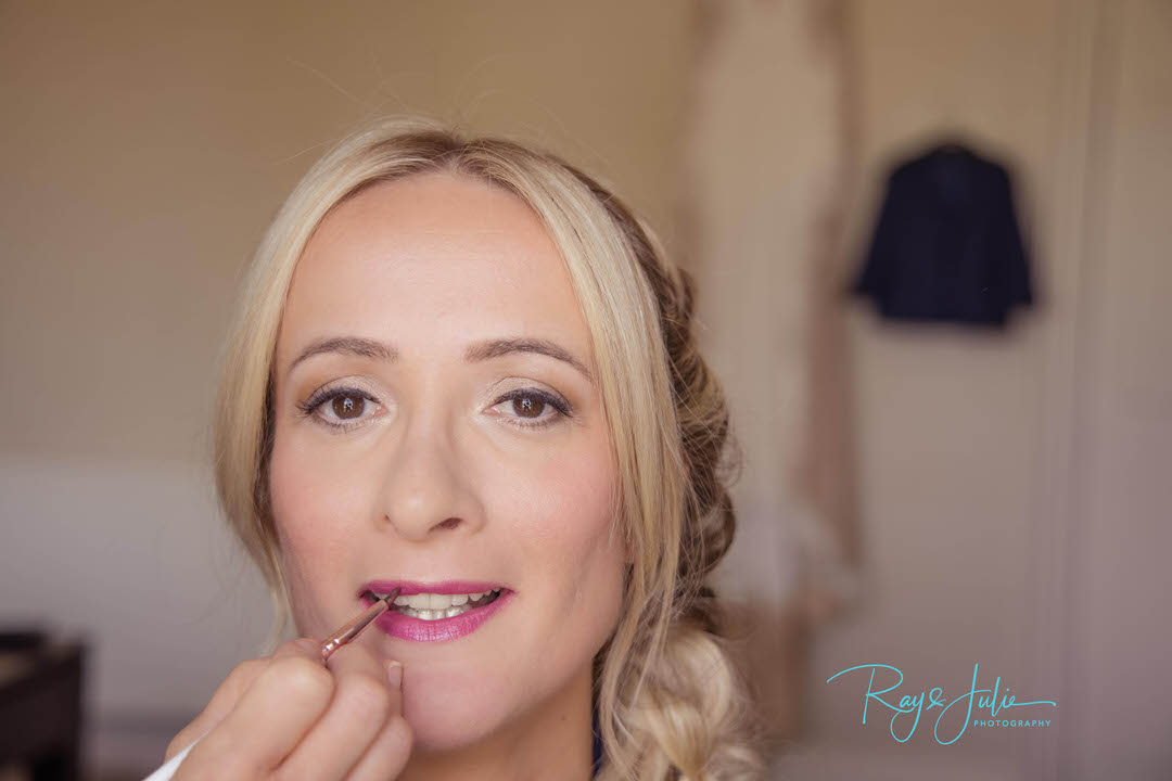 Bridal prep portrait with wedding dress and suit hanging up in the background