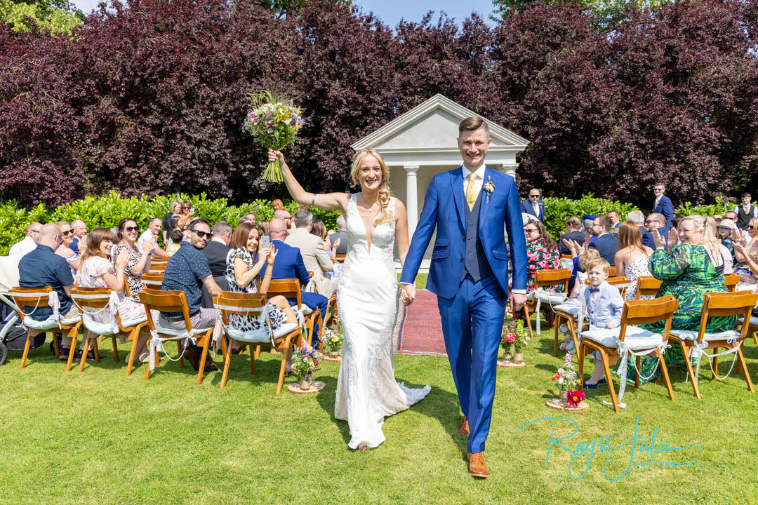 Bride and groom smiling after just getting married at Tickton Grange. Bride holding flowers in the air.