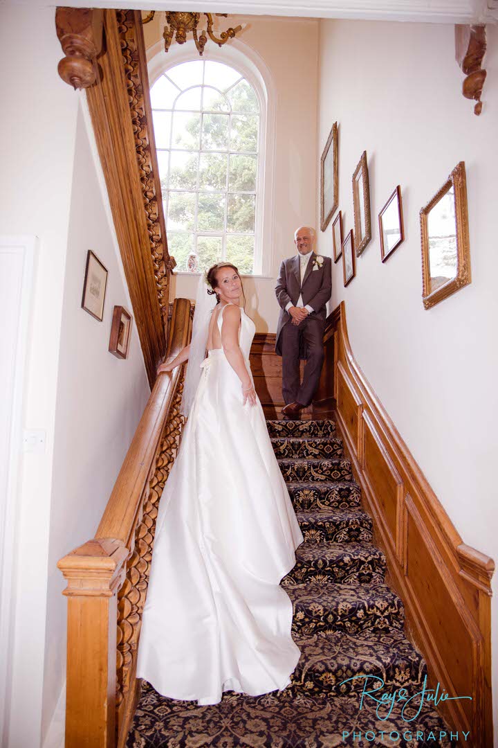 Wedding couple on the stairs at Rowley Manor Bride in a Deborah Moore wedding dress