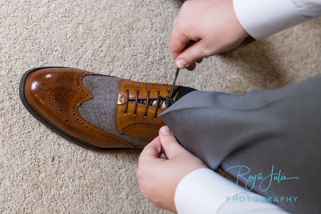 Groom tying up his wedding shoes