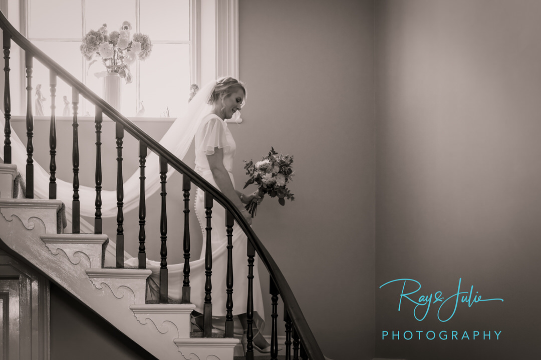 Bride walking downstairs with wedding bouquet in her hands - beautiful wedding black and white photo